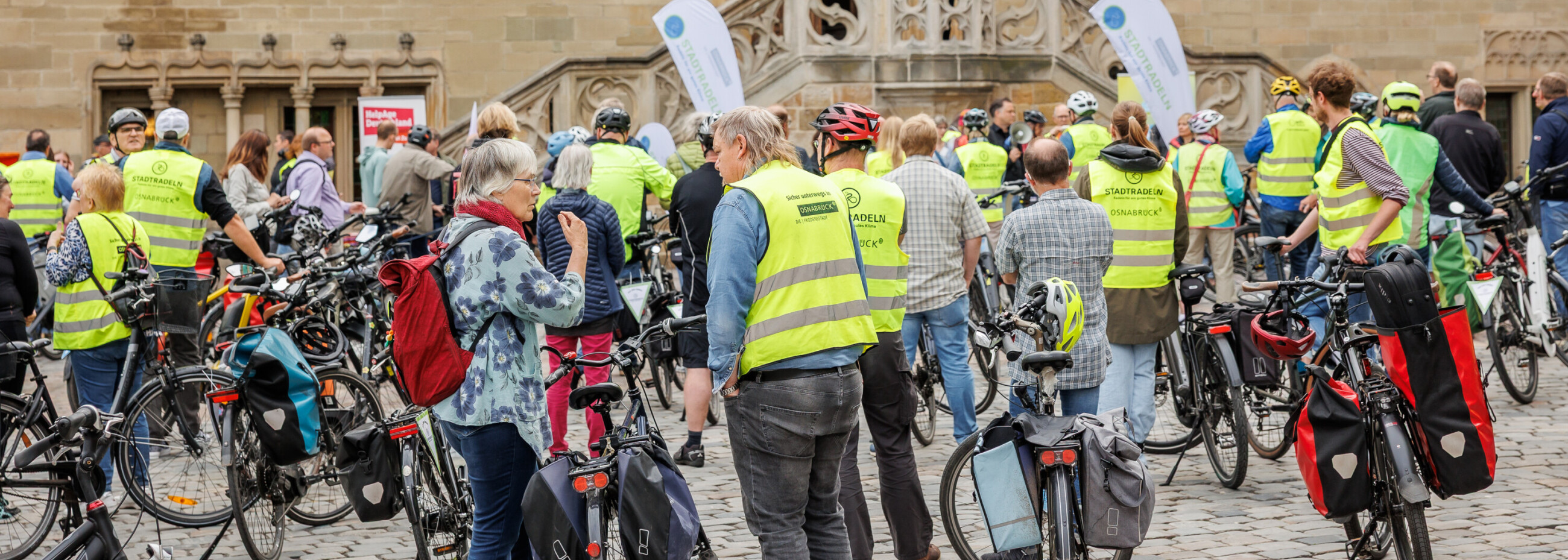Personen stehen mit Fahrrädern auf einem Rathausplatz