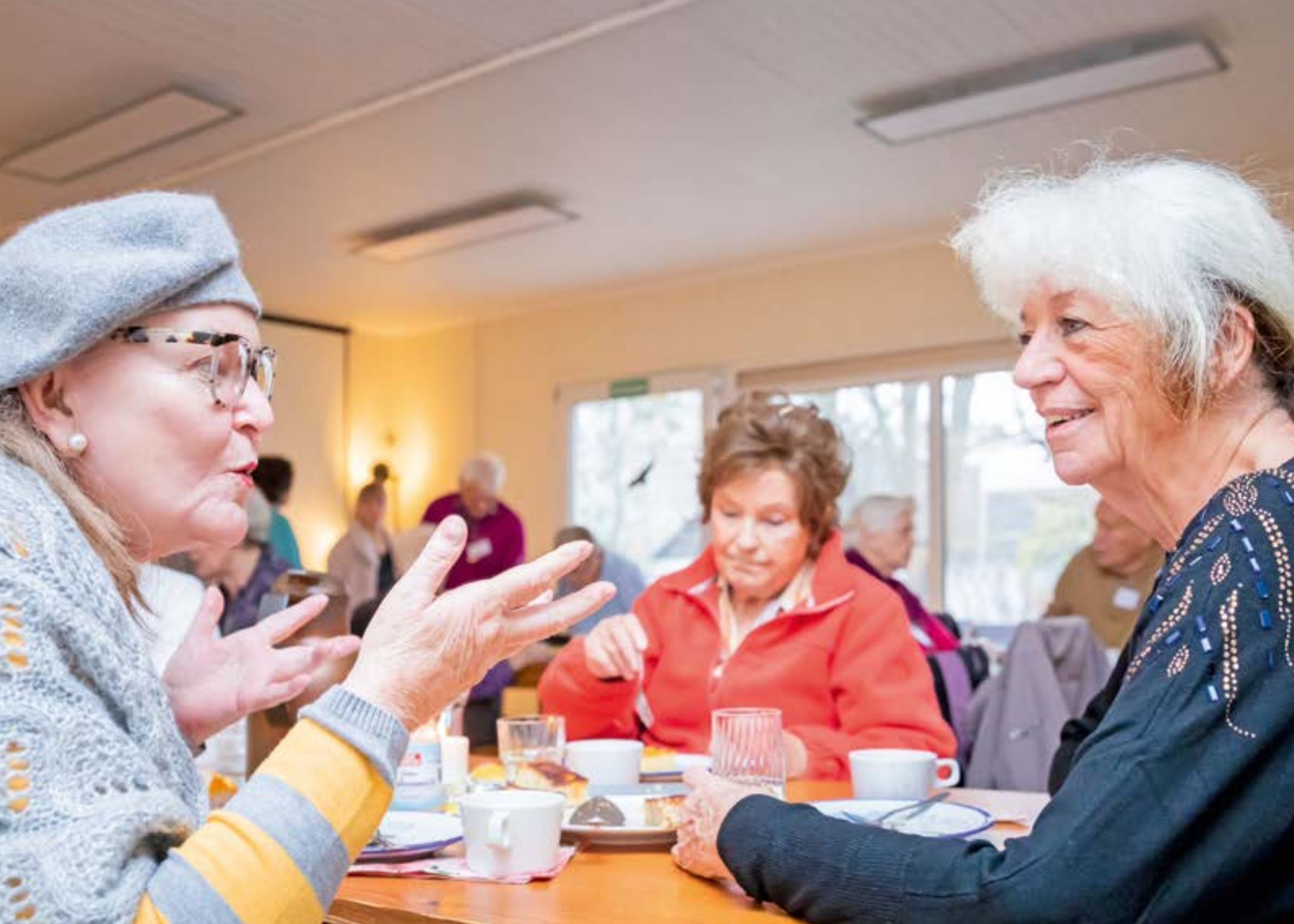 Personen sitzen am Tisch und sprechen miteinander