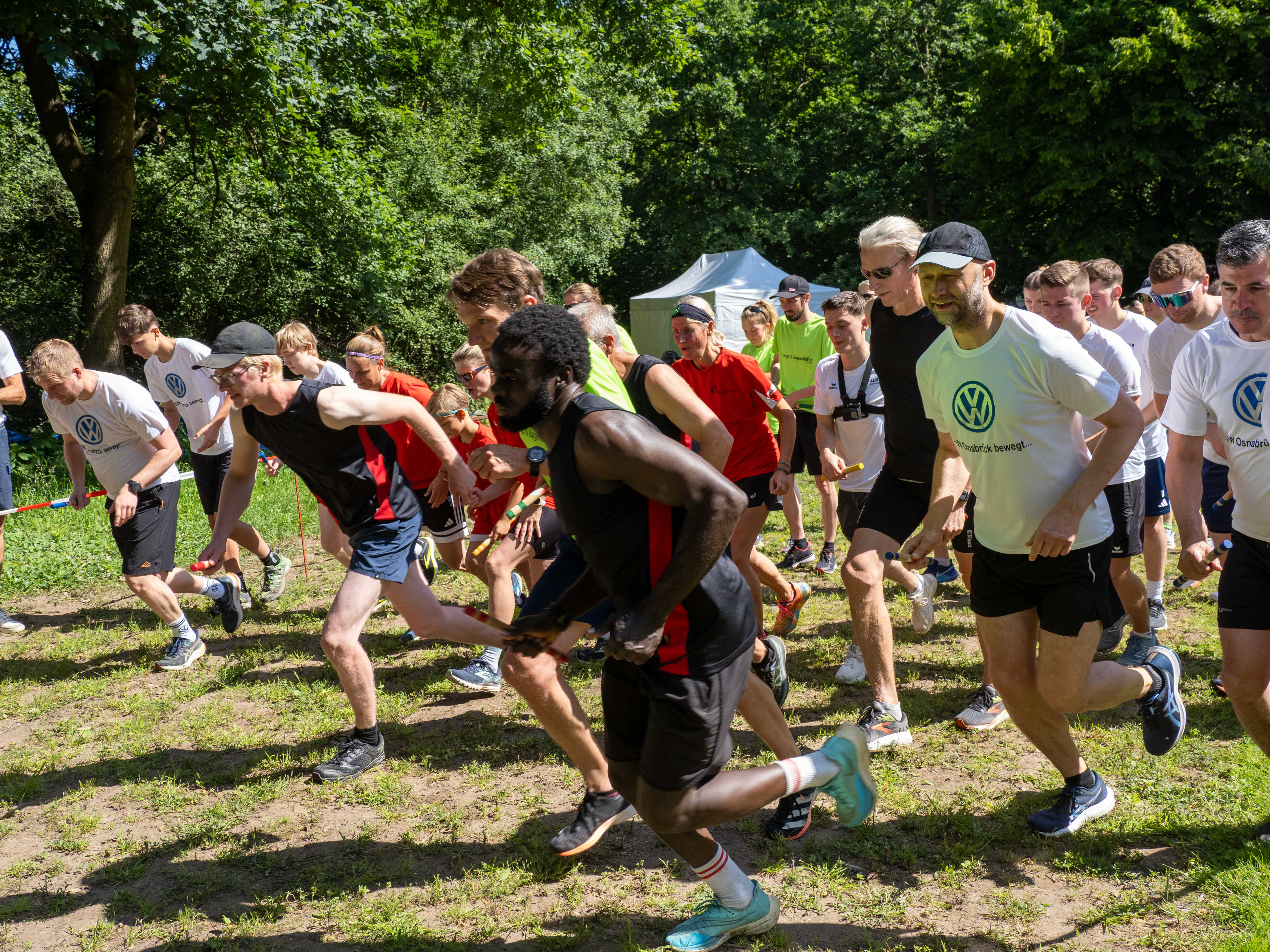 „Start des Firmenstaffellaufs 2025 in Osnabrück – motivierte Läuferinnen und Läufer verschiedener Teams starten gemeinsam ins Rennen bei sommerlichem Wetter.“.