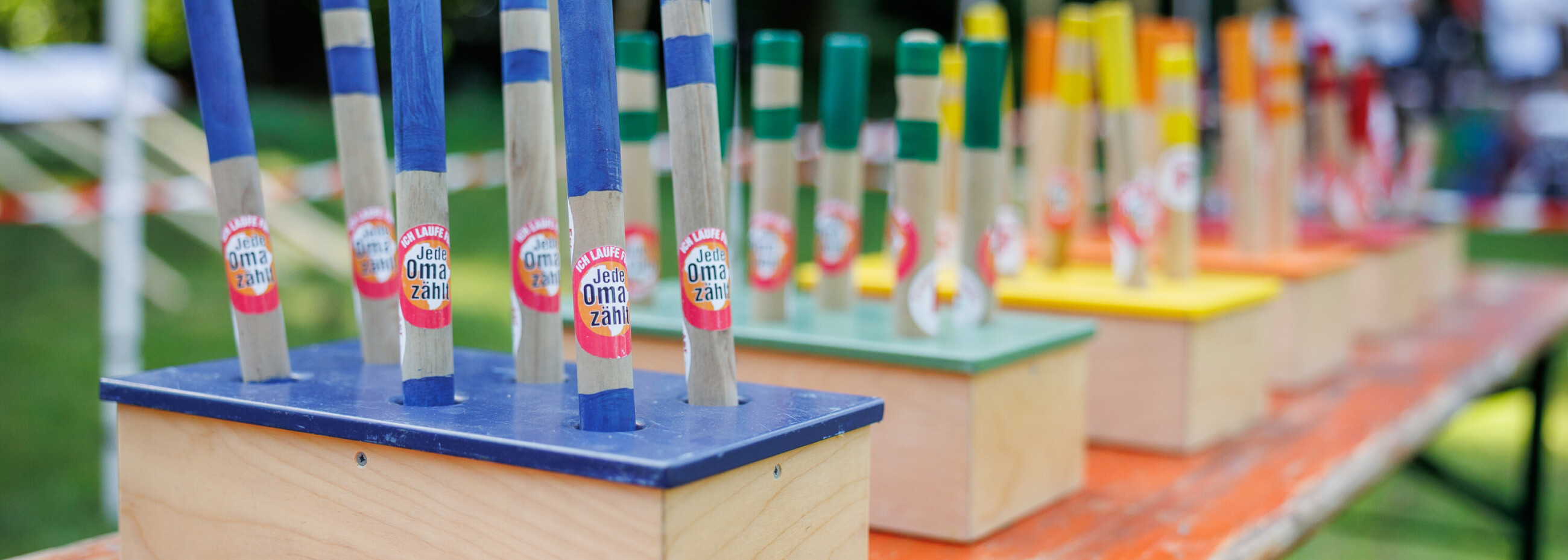 „Bunte Staffelstäbe mit der Aufschrift ‚Jede Oma zählt‘ beim Firmenstaffellauf 2025 in Osnabrück, bereit für die teilnehmenden Teams.“