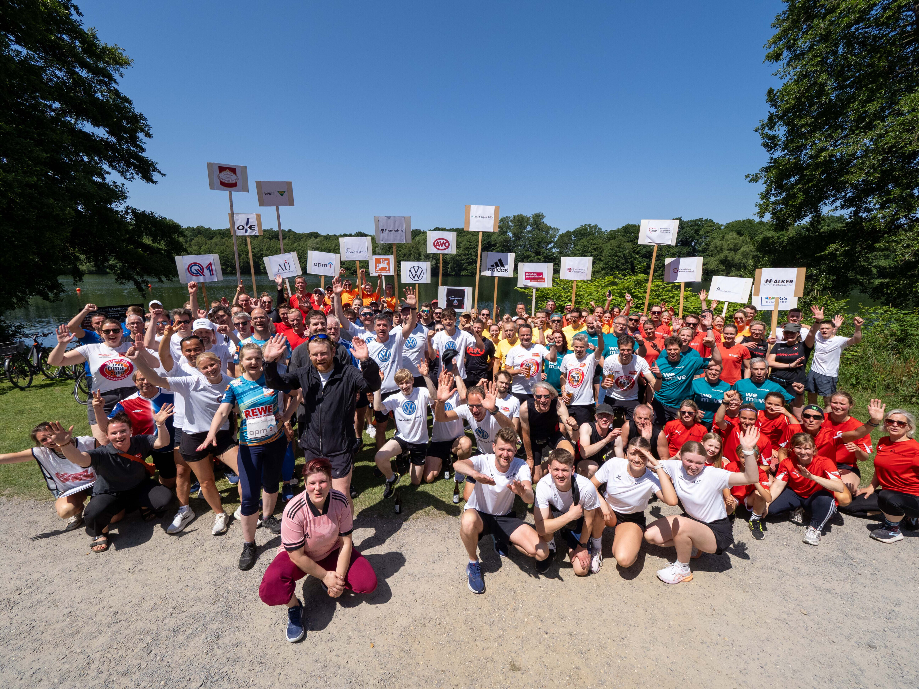 „Gruppenfoto aller teilnehmenden Teams beim Firmenstaffellauf 2025 in Osnabrück – sportliche Stimmung und Teamgeist am Ufer des Rubbenbruchsees.“.