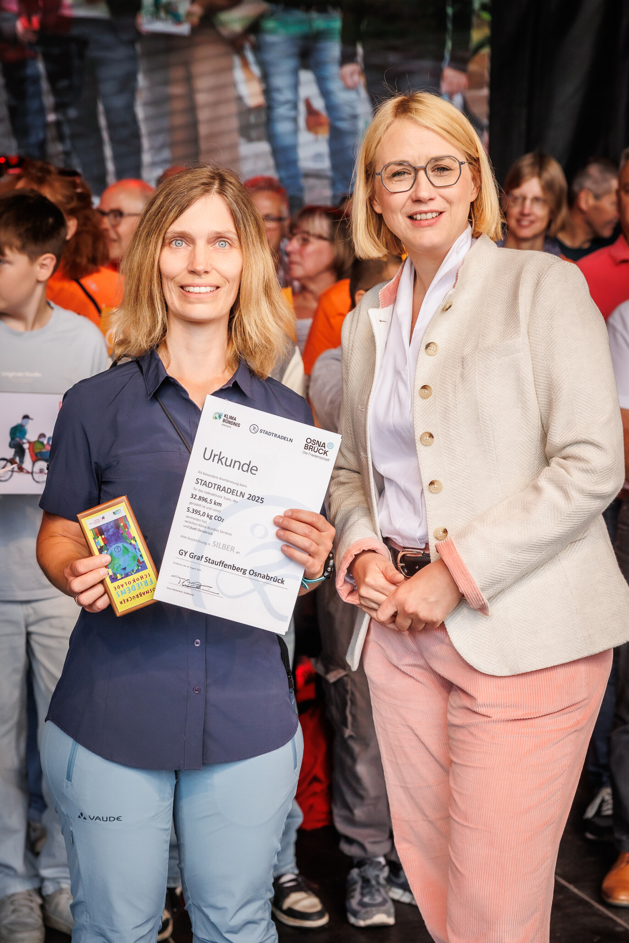 ertreterin des Graf-Stauffenberg-Gymnasiums in Osnabrück zeigt ihre Urkunde und ein Geschenk bei der Preisverleihung des Charity Stadtradelns 2025.