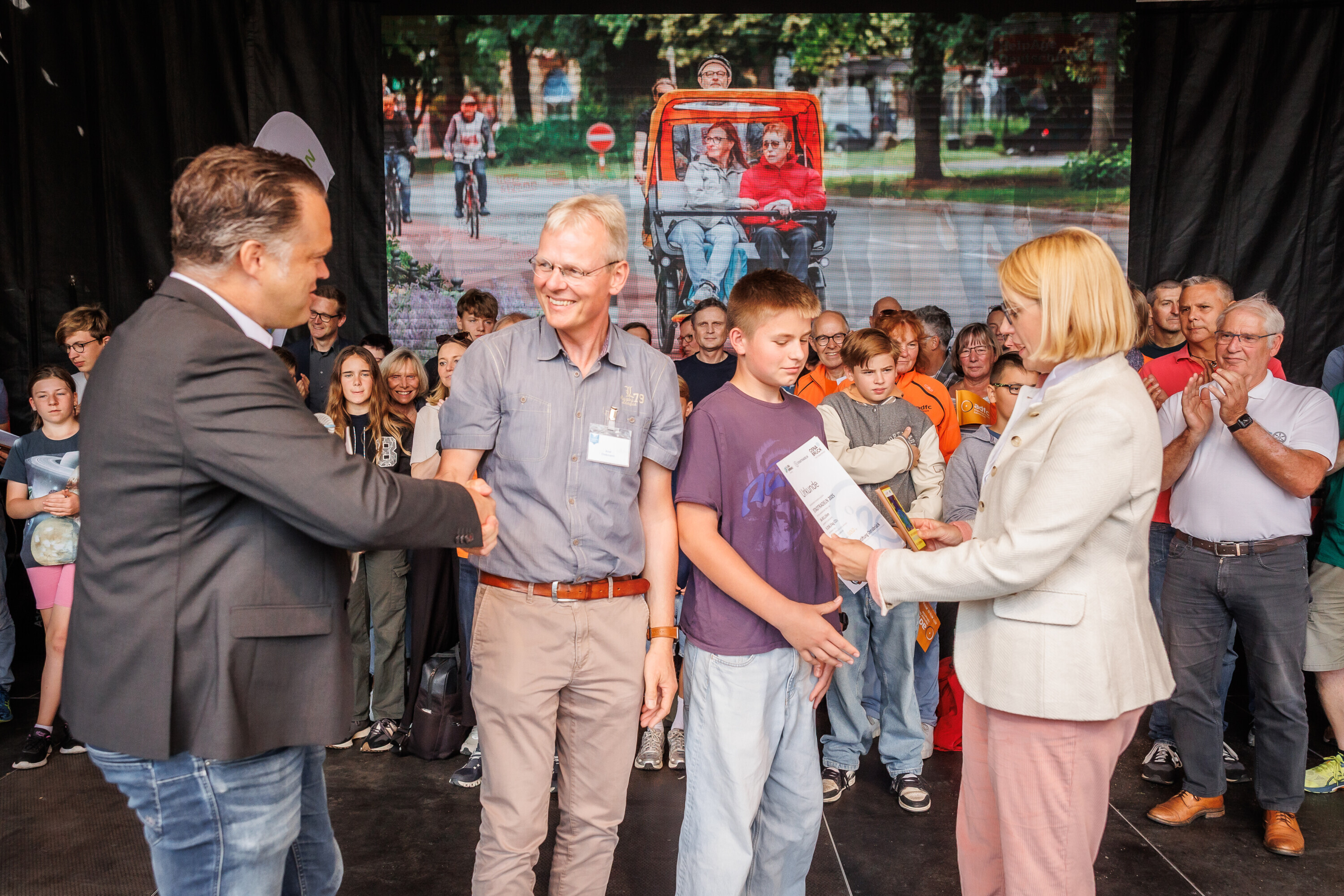 Vertreter der Katholischen Schulstiftung nehmen gemeinsam mit einem Schüler ihre Auszeichnung beim Charity Stadtradeln 2025 entgegen.