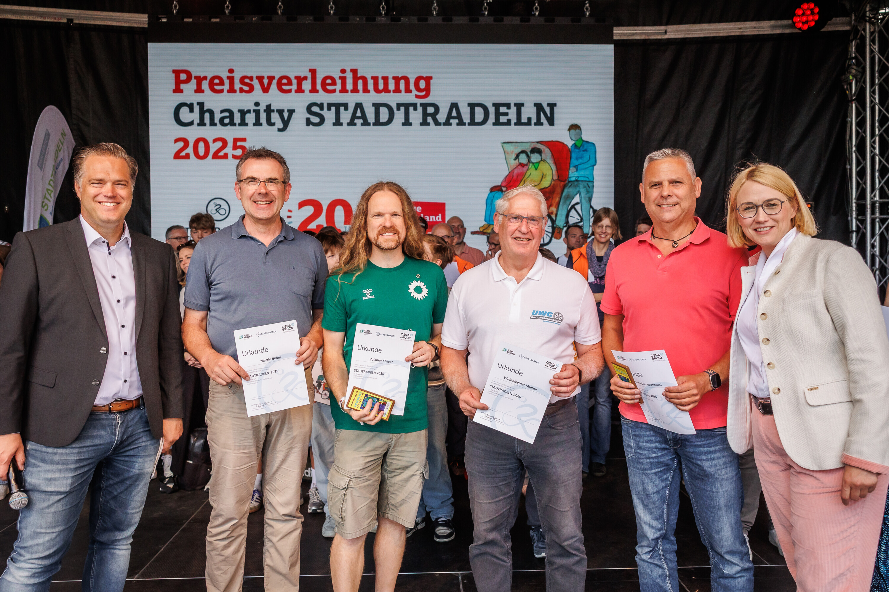 Mehrere Ratsmitglieder der Stadt Osnabrück stehen auf der Bühne und präsentieren ihre Urkunden beim Charity Stadtradeln 2025.