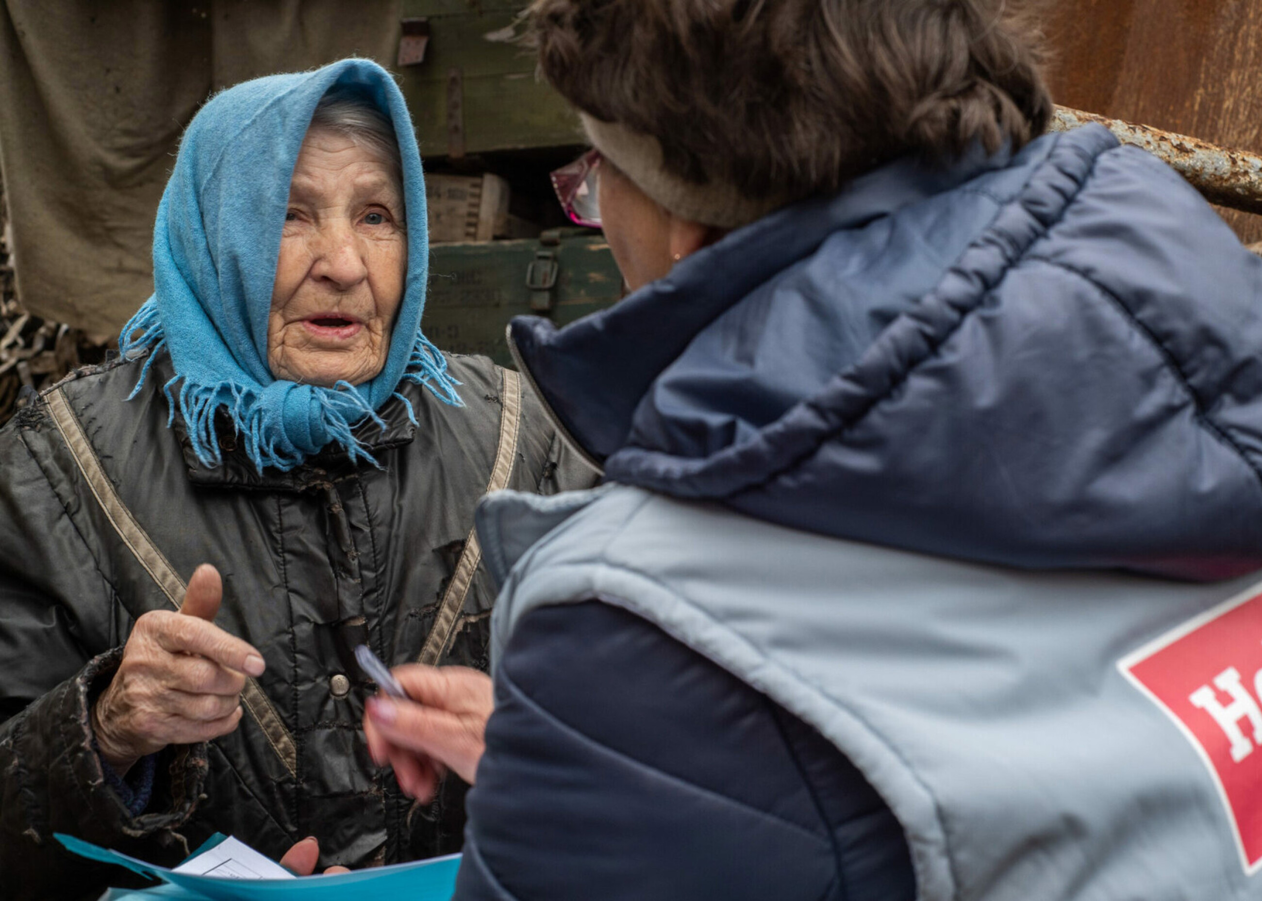 Eine ältere Frau in der Ukraine erzählt einer Mitarbeiterin von HelpAge, was sie benötigt.