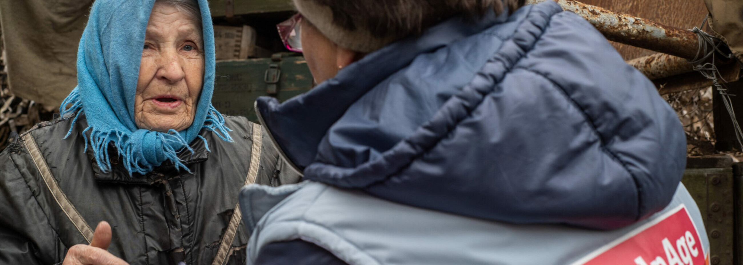 Eine ältere Frau in der Ukraine erzählt einer Mitarbeiterin von HelpAge, was sie benötigt.