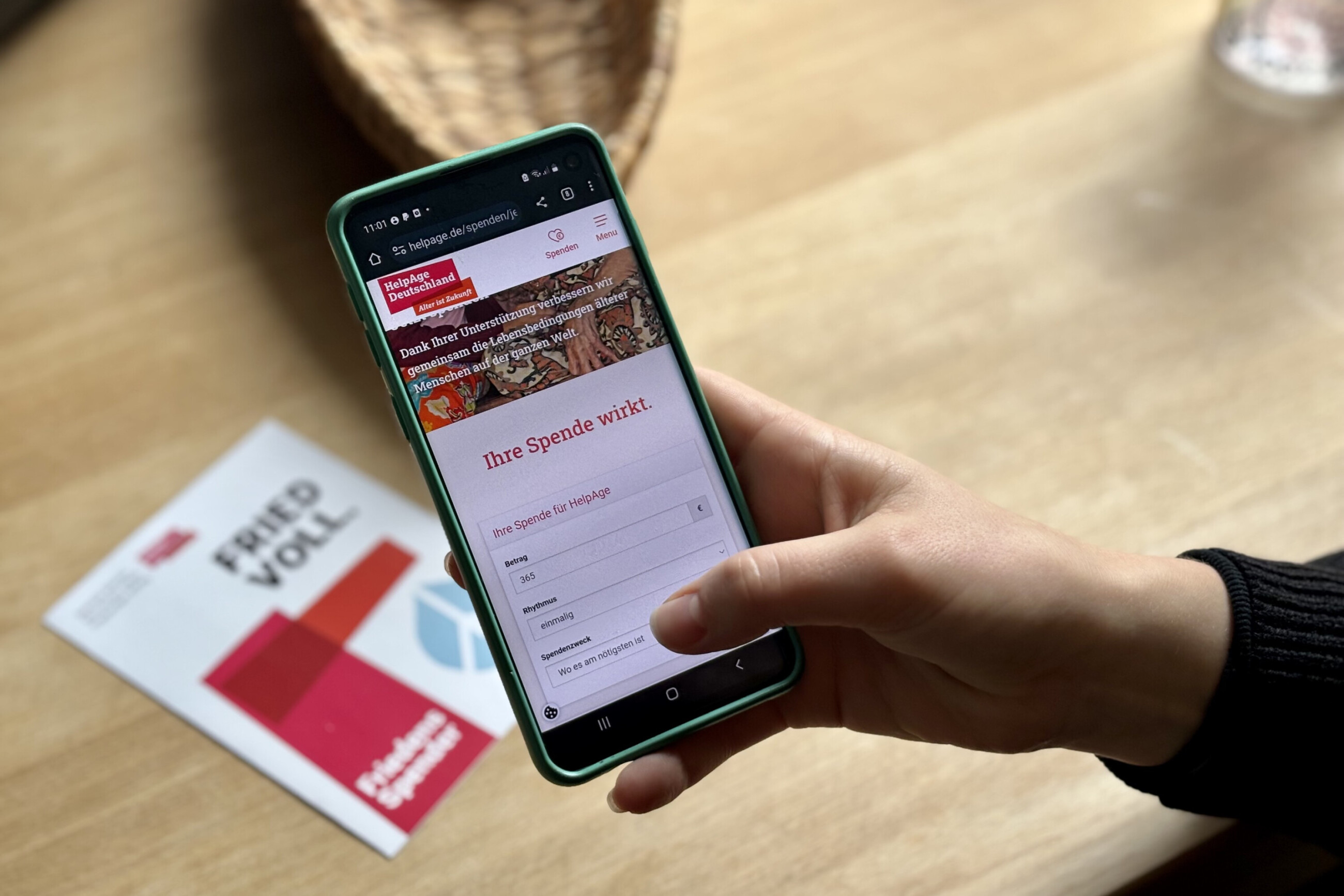 Person hält ein Smartphone mit einem Spendenformular von HelpAge Deutschland in die Kamera