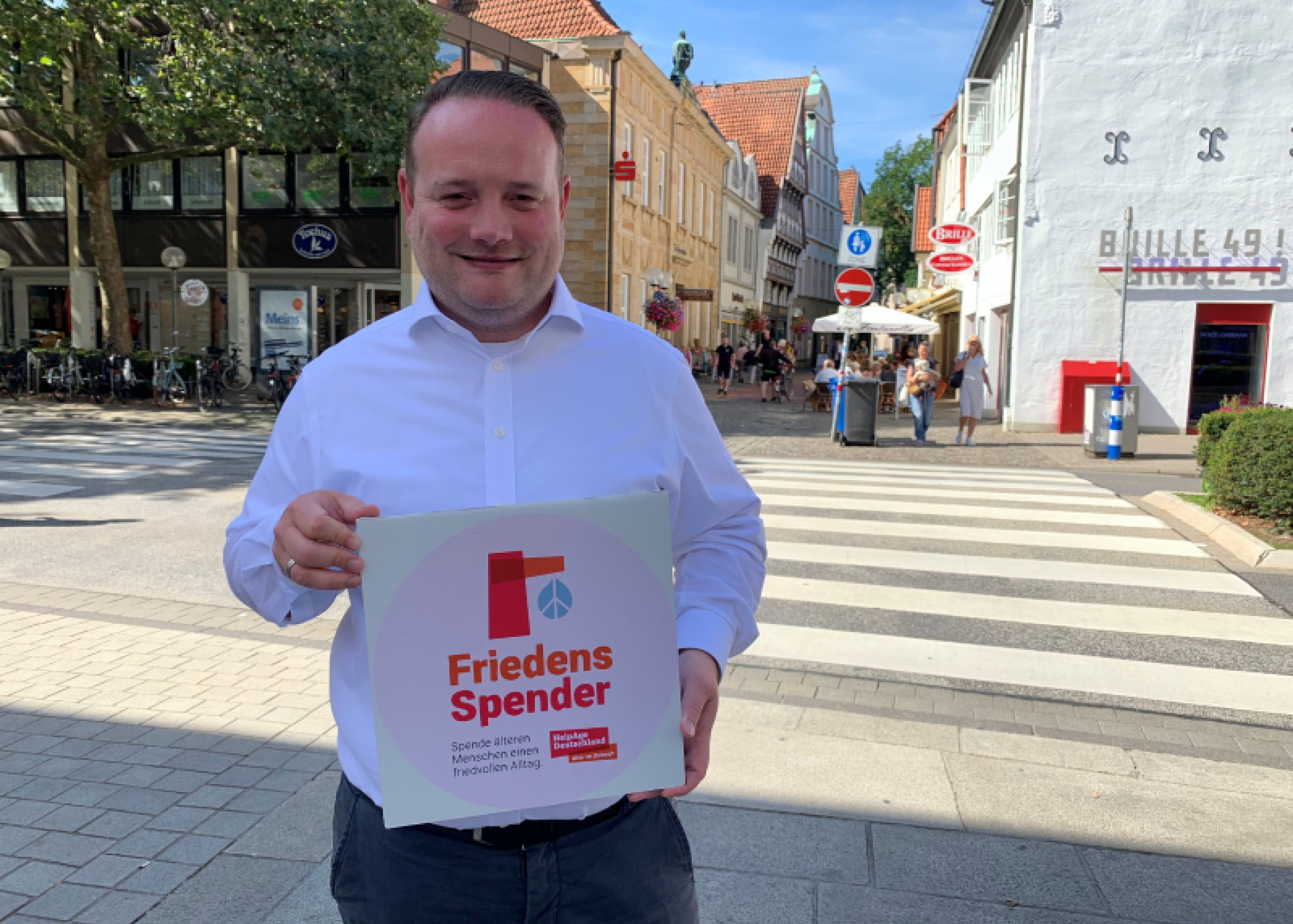 Person hält in der Innenstadt das Logo vom FriedensSpender in die Kamera