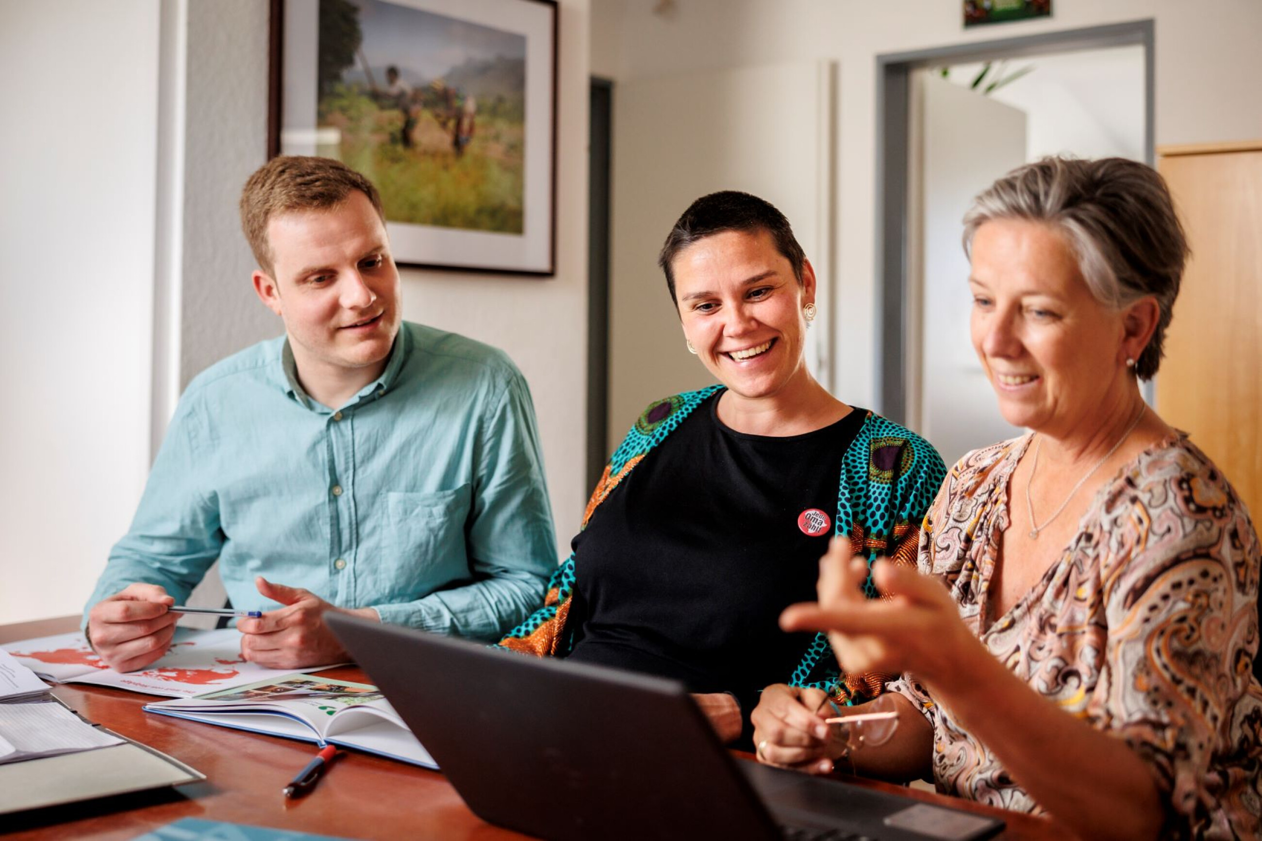 Personen schauen auf einen Laptop und freuen sich
