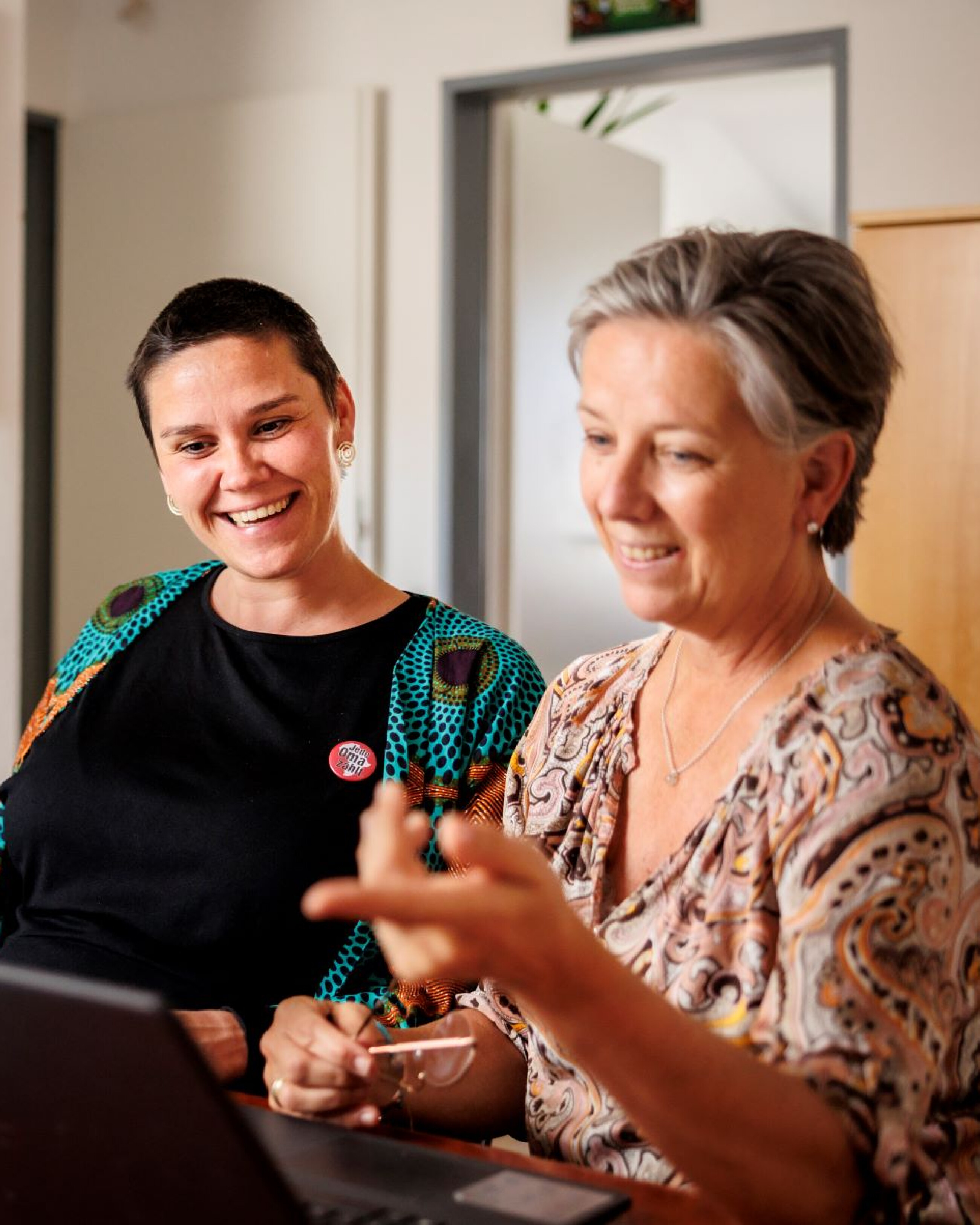 Personen schauen auf einen Laptop und freuen sich